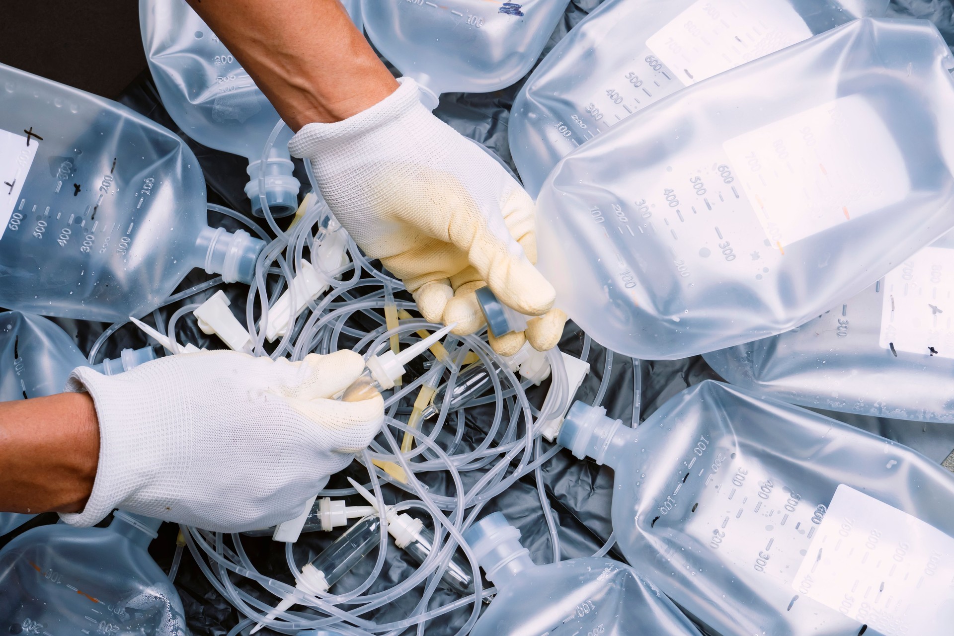 Hands of male officers sorting toxic waste, IV tubes, extension tubes, Intravenous therapy acetate ringer's injections, saline bottles, and Syringes, from clinics or hospitals for recycling
